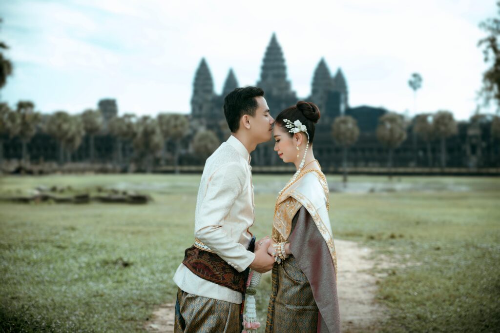 A couple in traditional clothing standing in front of a temple