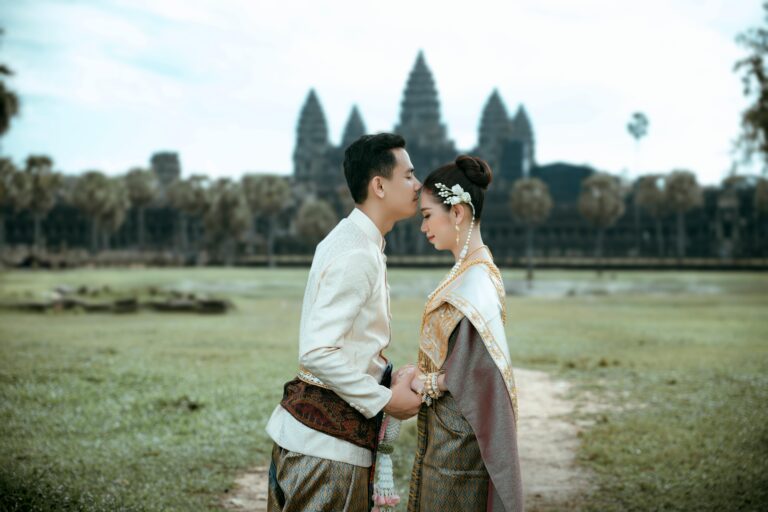 A couple in traditional clothing standing in front of a temple