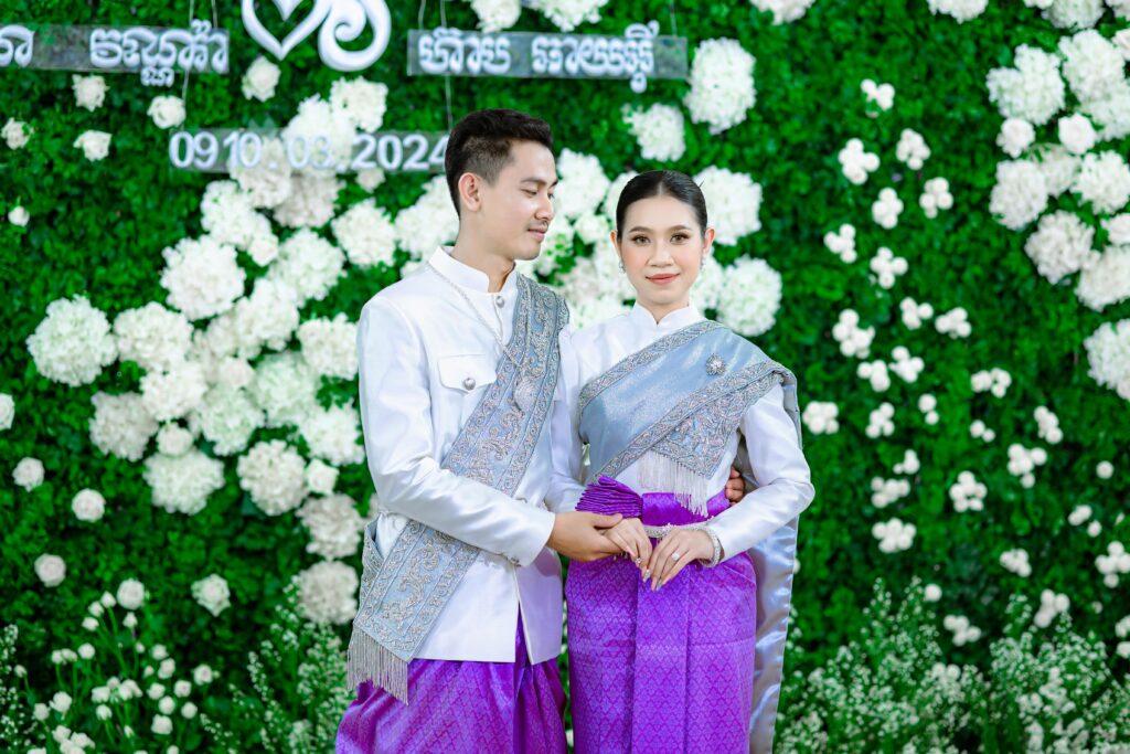 Groom and the Bride Standing Together against White Flowers