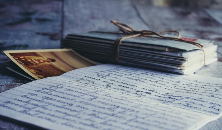 Stack of vintage letters and photographs tied with string on a rustic wooden table.