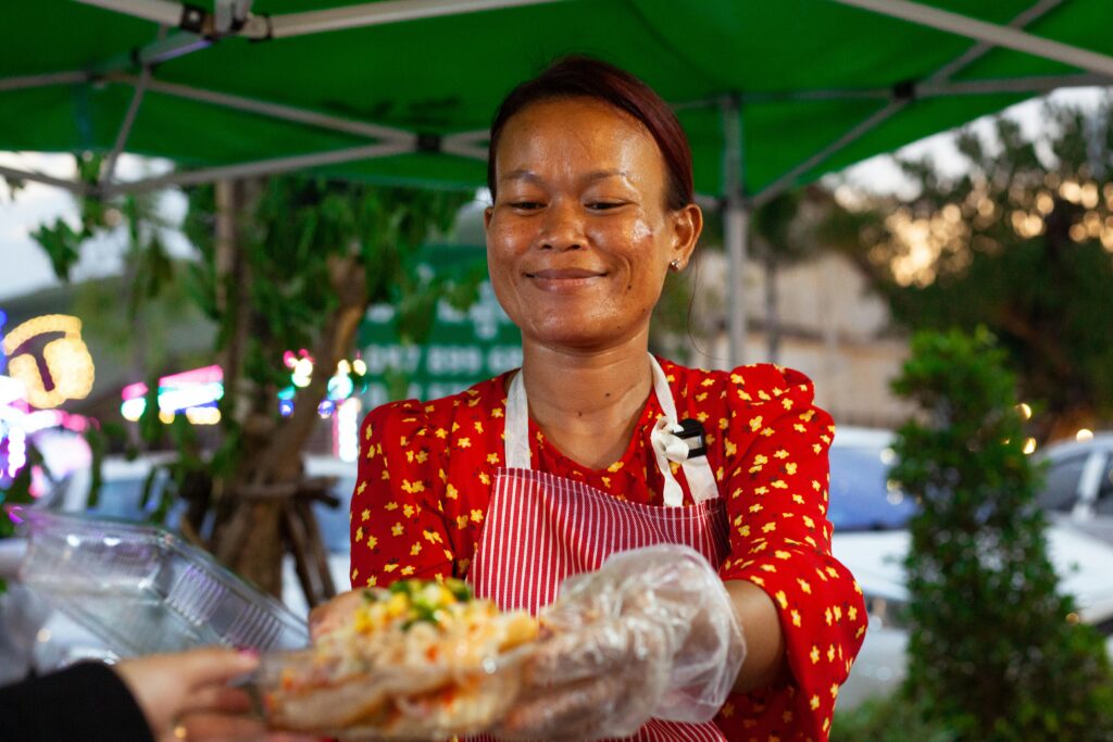 Smiling Woman Selling Food on a Street