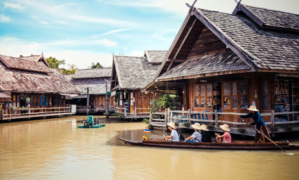 Explore the vibrant and traditional floating market in Thailand, with wooden houses and tourists on boats.