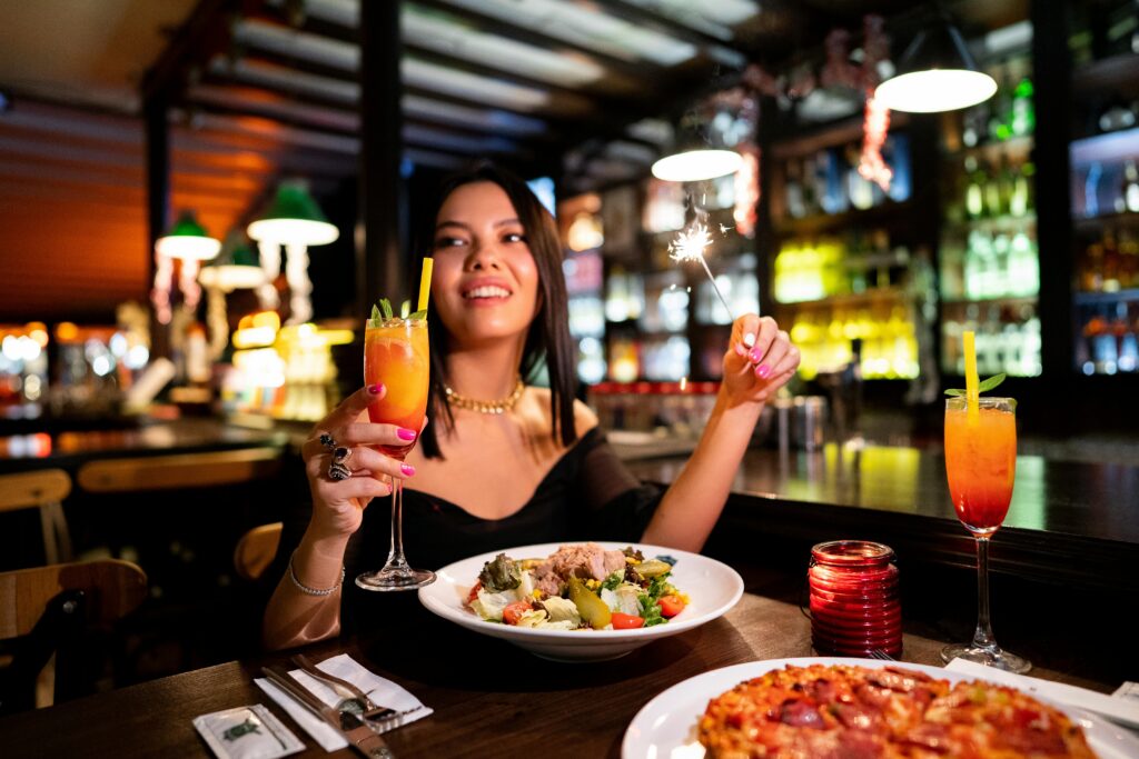 Woman enjoying a festive dinner with cocktails in a lively Istanbul restaurant.