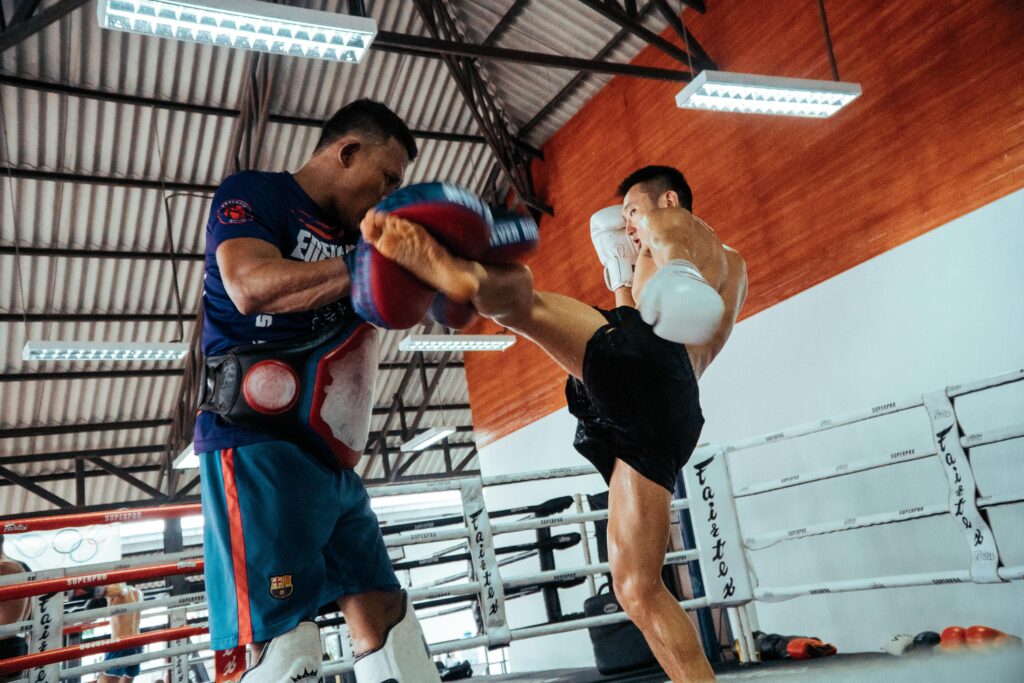 Two fighters engage in a dynamic Muay Thai training session inside a gym.