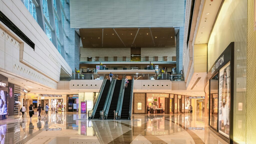 Modern shopping mall interior with escalators and luxury stores in Hong Kong.