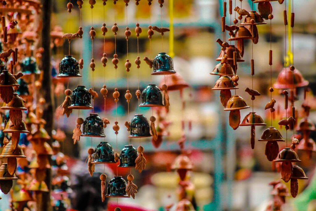 Vibrant hanging bells and ornaments in a pottery market stall, showcasing cultural artistry.