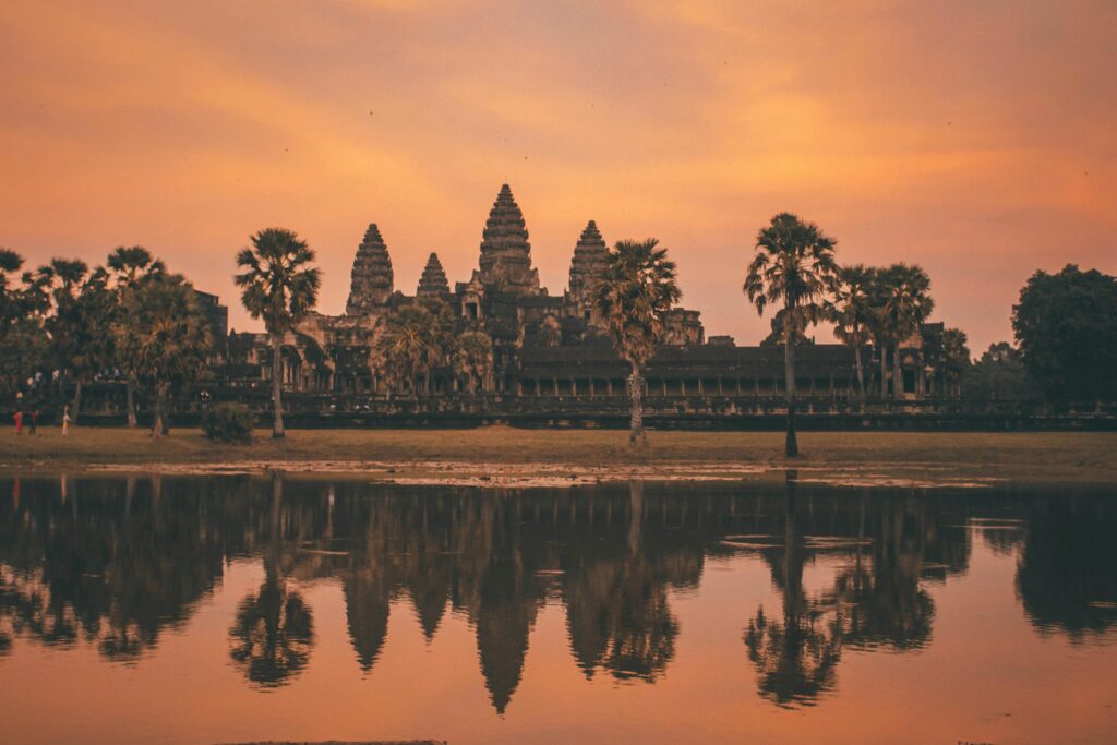 Tranquil sunrise view of Angkor Wat reflecting in calm lake waters, Siem Reap, Cambodia.