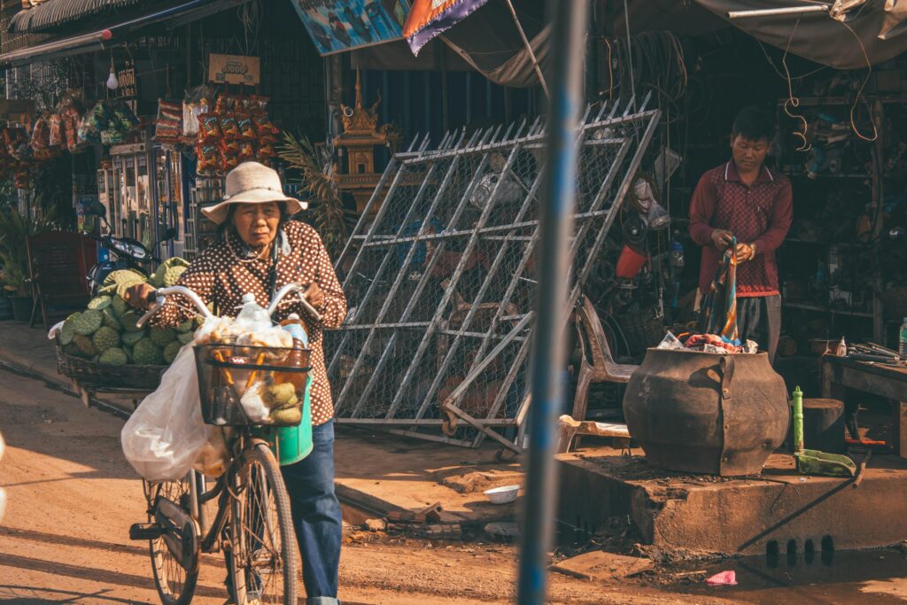 Elderly woman selling fruits on a bicycle in Siem Reap market street, Cambodia.