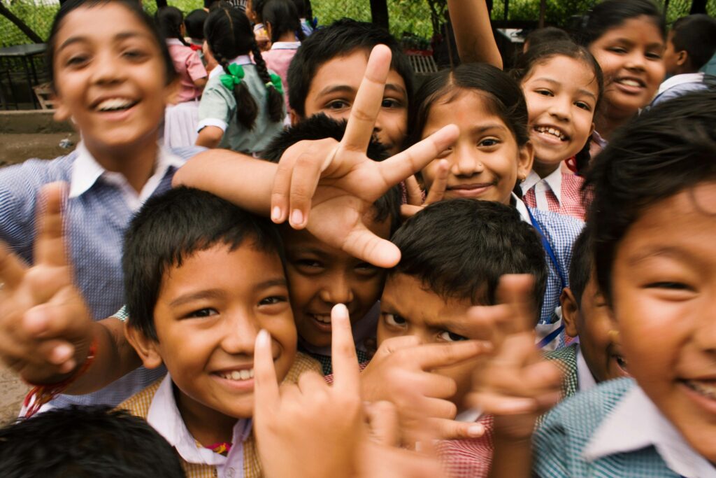 A joyful group of children smiling and making playful gestures outdoors in siem reap.